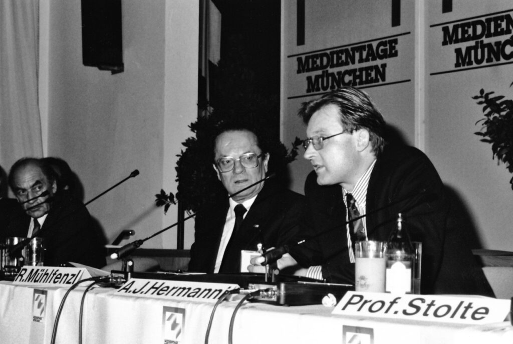 Professor Hermanni auf den Münchner Medientage 1988. Auf dem Podium v.l.n.r: Hans Bausch (Intendant des Süddeutschen Rundfunks), Rudolf Mühlfenzl (Präsident der Bayerischen Landeszentrale für Neue Medien), Alfred-Joachim Hermanni (Chefredakteuer von Eureka-Television) und Professor Dieter Stolte (Intendant des Zweiten Deutschen Fernsehens; verdeckt im Bild).